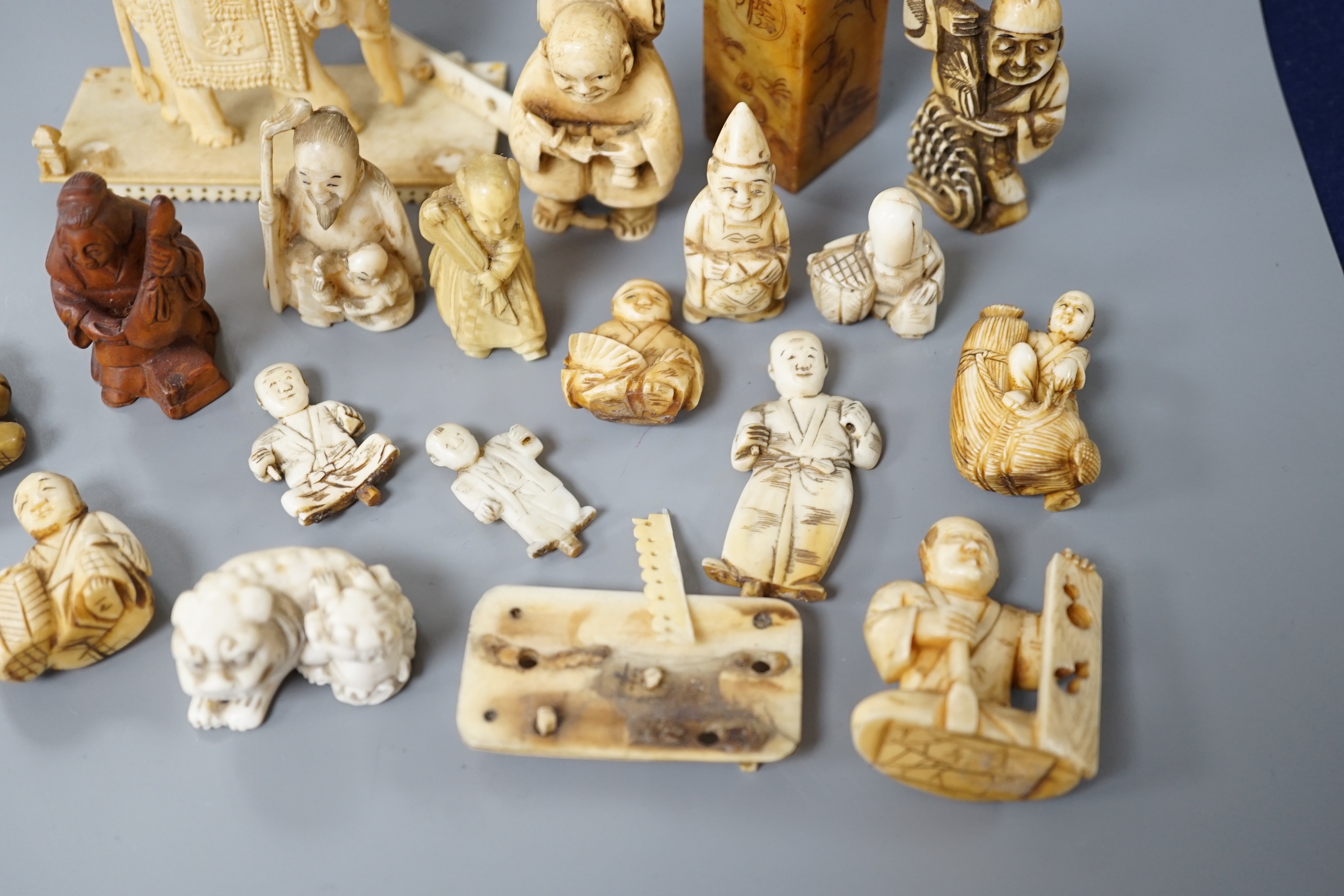 A collection of various ivory carvings including netsuke, a soapstone seal and carved wood netsuke